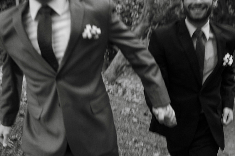 Gay male couple runs at the conclusion of their wedding ceremony.