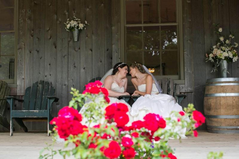 Wedded couple sitting on the country porch with roses in bloom. Photo: Angelina M Photography