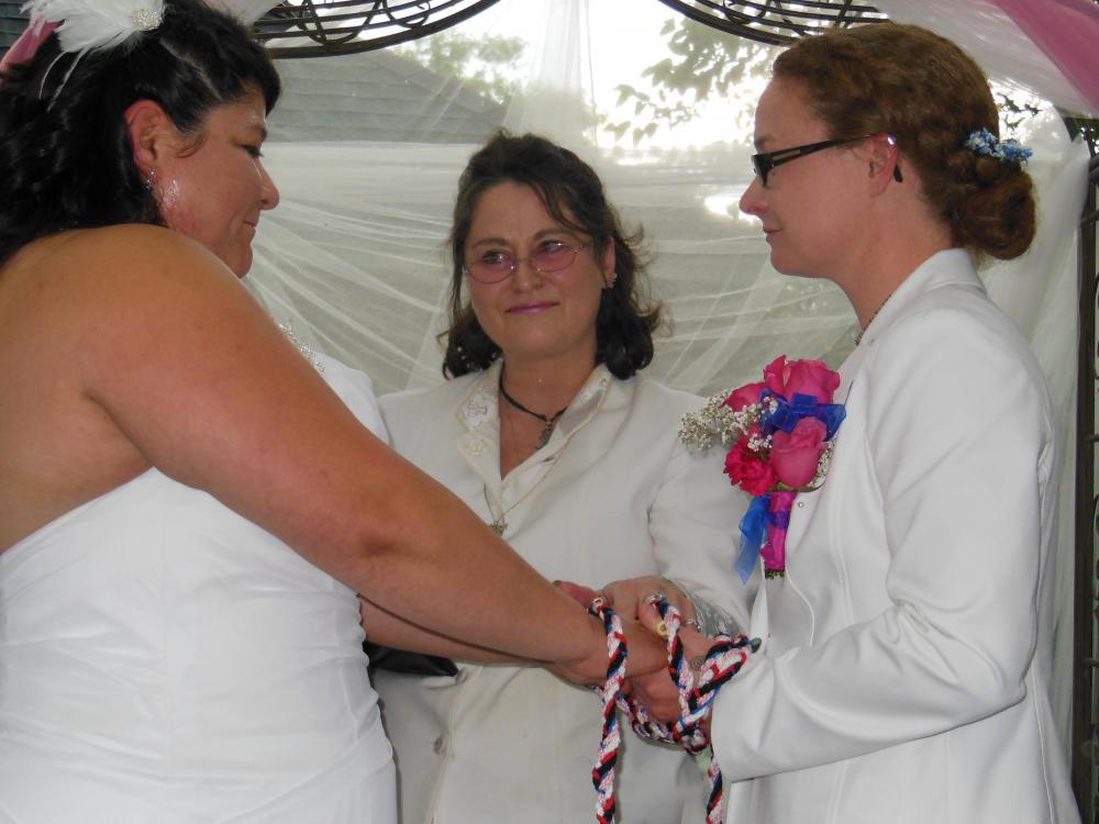 lesbian couple perform a handfasting wedding ceremony